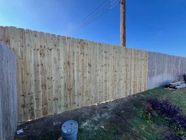 Newly installed pressure-treated wood privacy fence for residential backyard security.