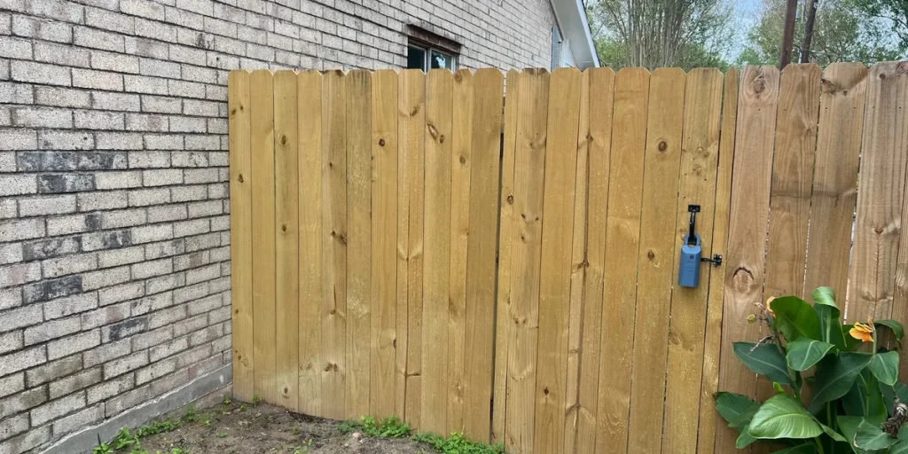 Secure wooden privacy fence with locked gate beside a brick wall
