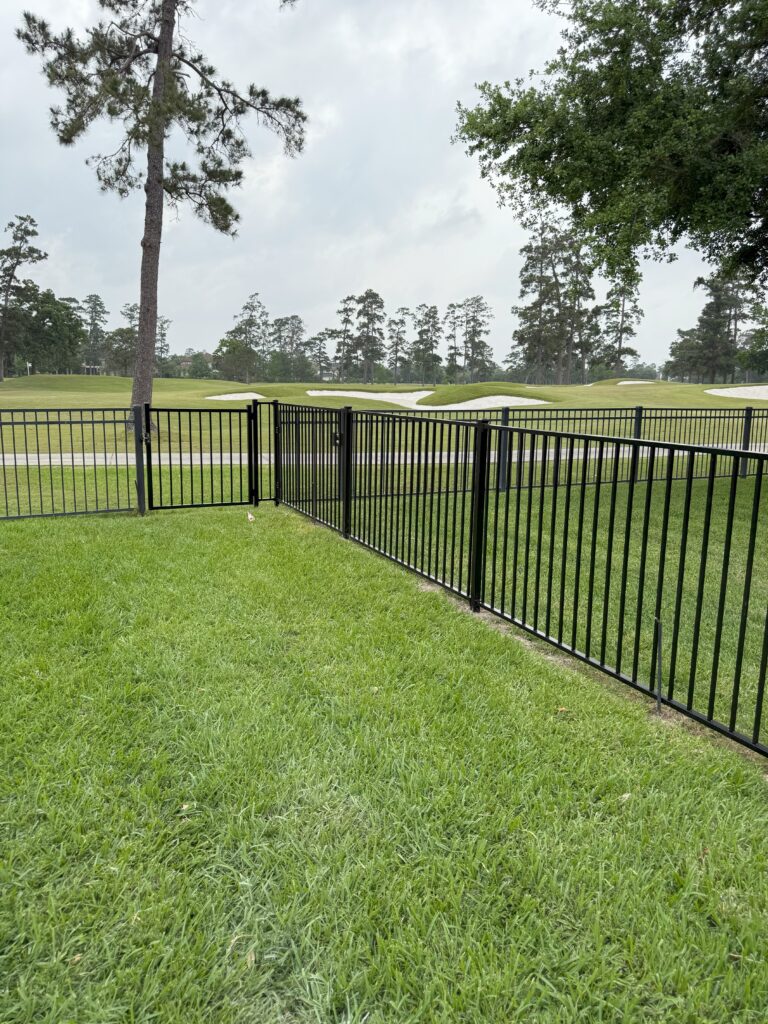 Black metal fence installation with gate on green lawn