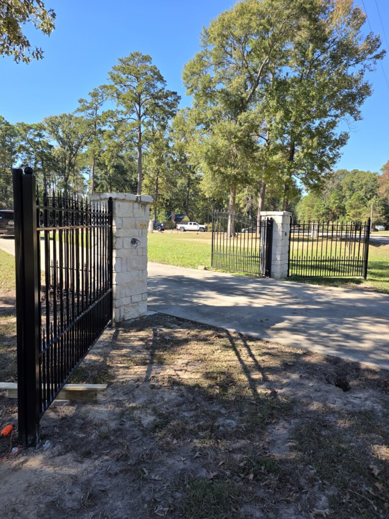 Wrought iron driveway gate with stone pillars.