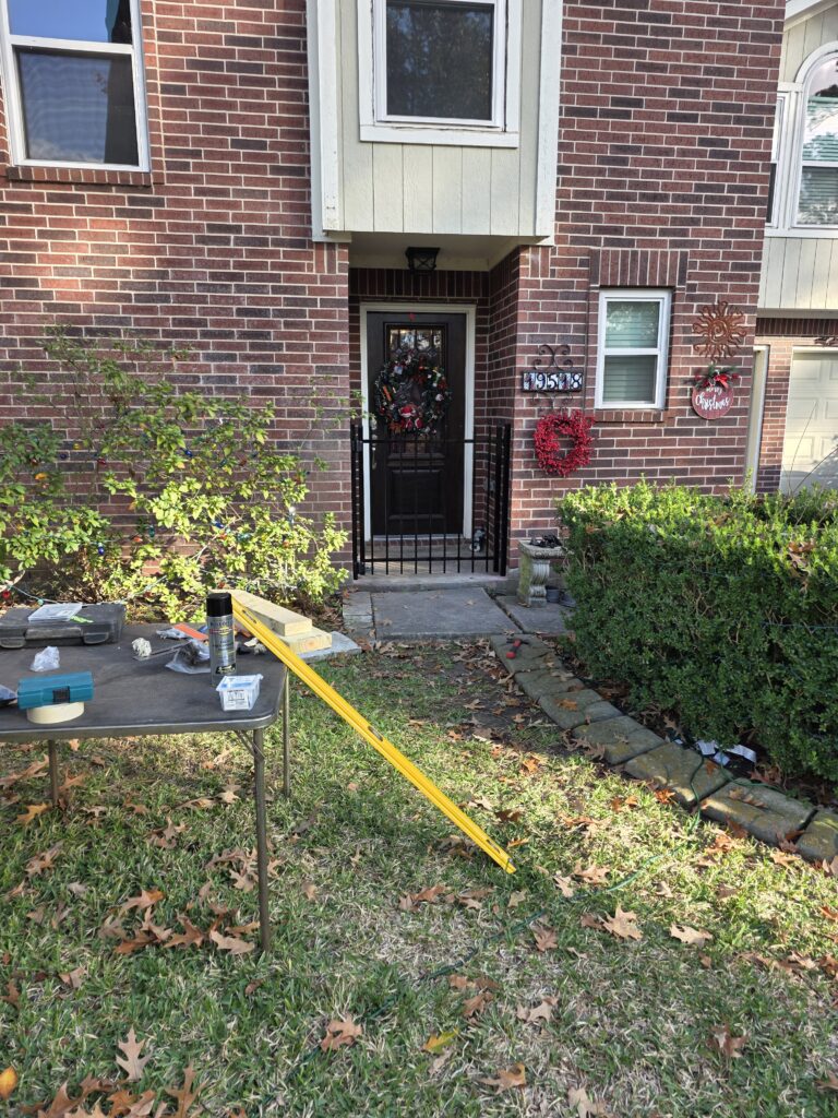 Black metal security gate installed at a brick house entrance.