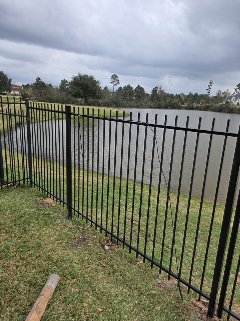 Black metal fence installed along a waterfront property line.