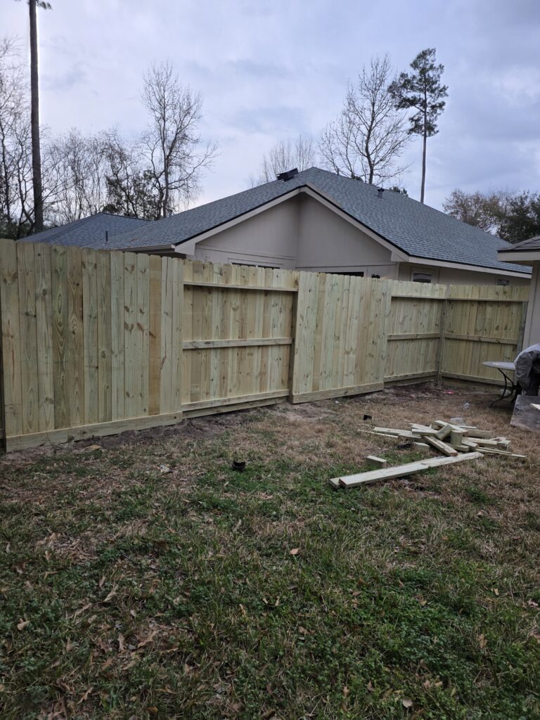 Pressure-treated cedar wood privacy fence installation in a residential backyard.